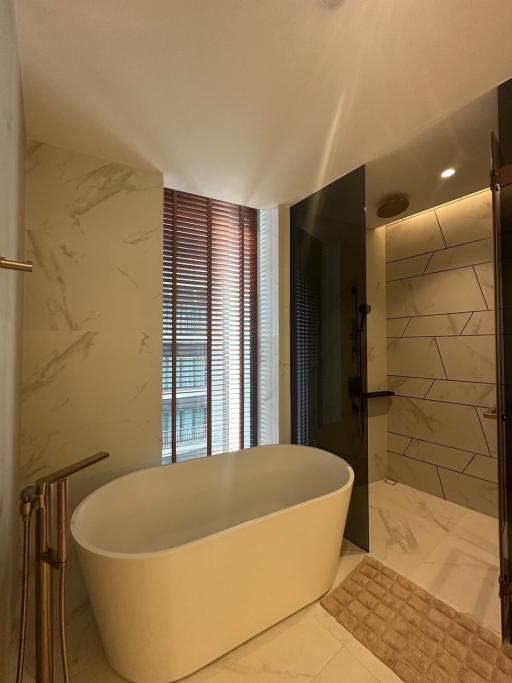 Elegant bathroom with freestanding tub, marble tiling, and natural light