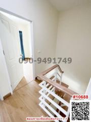 Bright staircase area leading to the upper floor of a residential property with wooden banisters