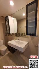 Modern bathroom interior with wall-mounted sink, mirror cabinet, and toilet