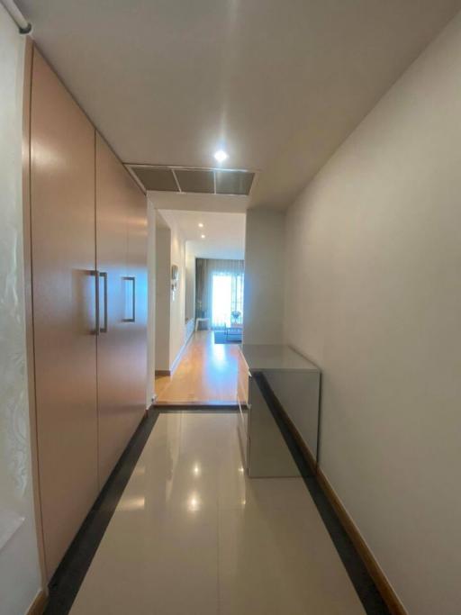 Modern hallway with reflective flooring and ceiling lights leading to a living area