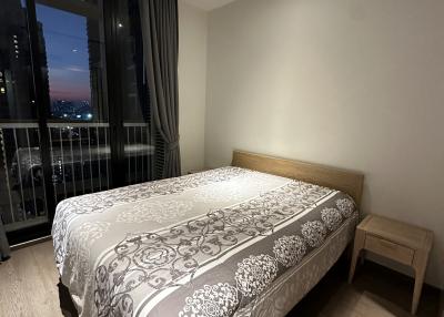 Cozy bedroom with a double bed and city view at dusk
