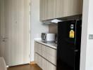 Modern kitchen with wooden cabinets and black refrigerator