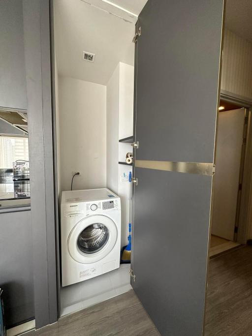 Compact laundry area with a modern washing machine and built-in shelves