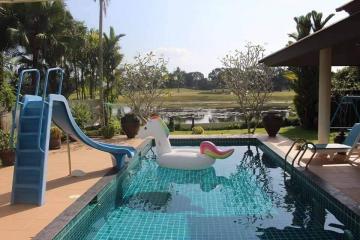 Backyard pool with a slide and inflatable toy overlooking a pond