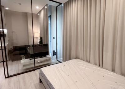 Modern bedroom with a view into the living area through glass walls