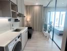 Modern laundry area with washing machine aside a compact living space with large windows and abundant natural light