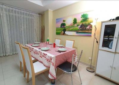 Cozy dining room with table set for dinner and a colorful countryside painting on the wall