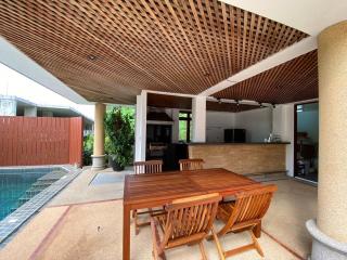 Spacious outdoor living area with dining set and kitchenette by a pool
