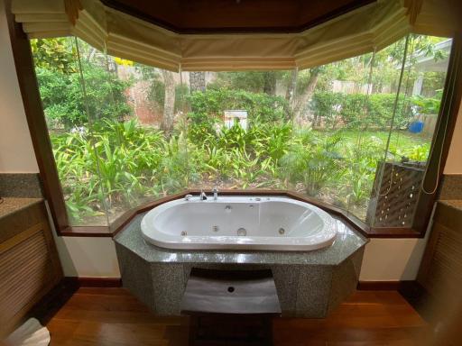 Elegant bathroom with a large Jacuzzi tub and a view of a lush garden