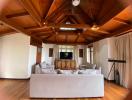Spacious living room with high cathedral ceiling, large windows, and wooden beams
