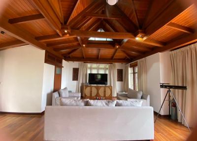 Spacious living room with high cathedral ceiling, large windows, and wooden beams