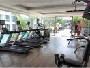 Modern gym in residential building with various equipment and residents exercising