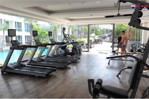 Modern gym in residential building with various equipment and residents exercising