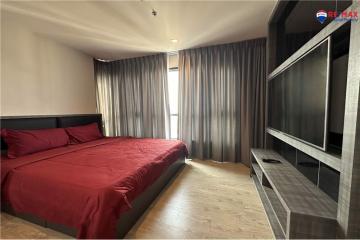 Modern bedroom with a red bedspread and dark curtains