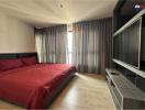 Modern bedroom with a red bedspread and dark curtains