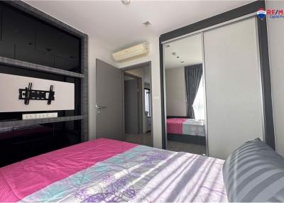 Modern bedroom with a large bed, mirrored wardrobe, and mounted TV