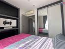 Modern bedroom with a large bed, mirrored wardrobe, and mounted TV