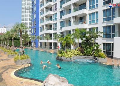 Luxury apartment complex with residents swimming in an outdoor pool surrounded by palm trees