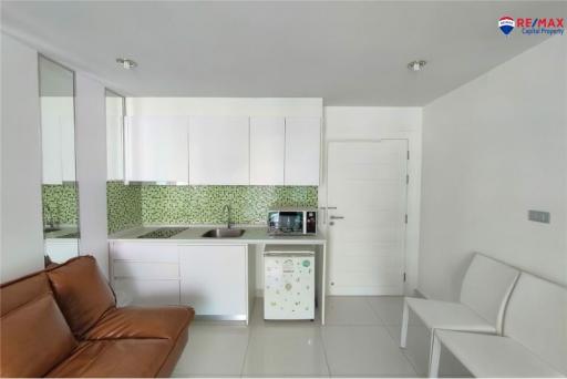 Modern kitchen with white cabinets and brown sofa