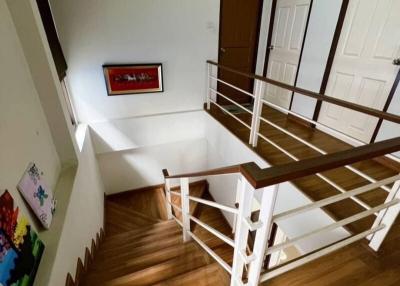 Wooden staircase leading to upper floor with white railing and hardwood floors