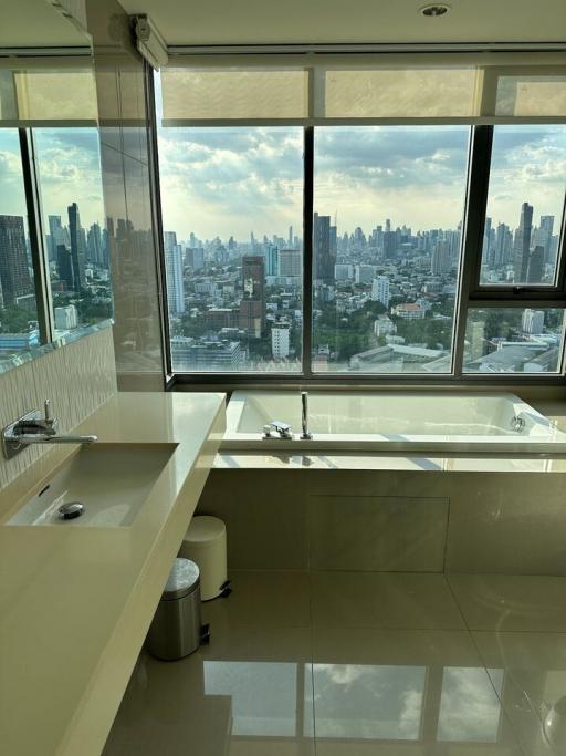 Modern bathroom with large windows overlooking the city skyline