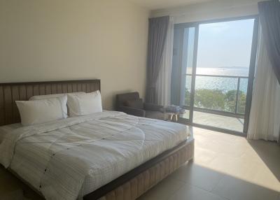 Bright bedroom with large bed and a scenic lake view through the balcony