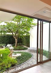 View of a serene garden from inside a home through large glass windows and doors