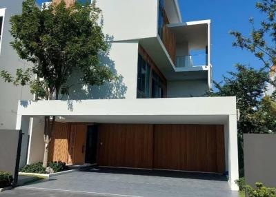 Modern two-story residential building with a wooden garage door and front balcony