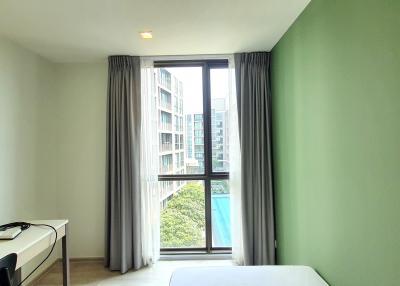 Bright and modern bedroom with large windows and green accent wall