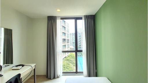 Bright and modern bedroom with large windows and green accent wall