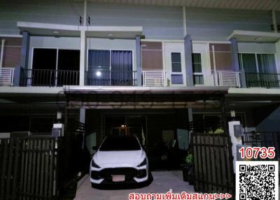Exterior night view of a residential townhouse with parked car