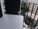 Compact balcony with city view and air conditioning unit