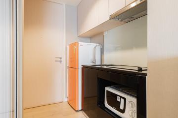 Compact Kitchen with Orange Refrigerator and Black Appliances