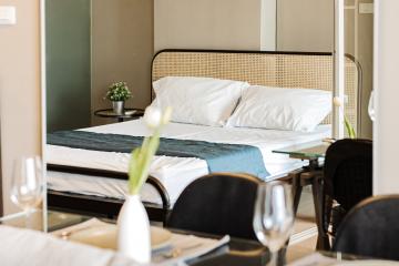 Elegant bedroom with a well-made bed, side table, and a glimpse of a dining area