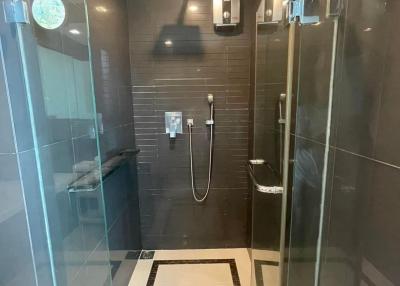 Modern bathroom with glass shower enclosure and dark tile walls
