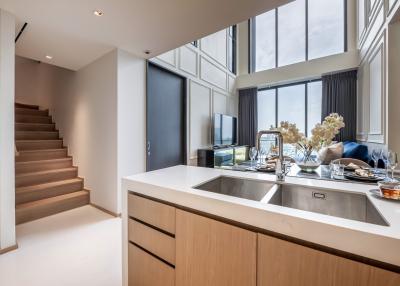 Modern kitchen with stainless steel appliances and staircase leading to the upper level