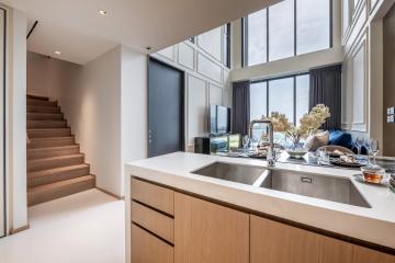 Modern kitchen with stainless steel appliances and staircase leading to the upper level