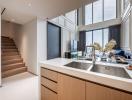 Modern kitchen with stainless steel appliances and staircase leading to the upper level