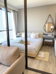 Cozy bedroom interior with a large bed, natural light, and a full-length mirror