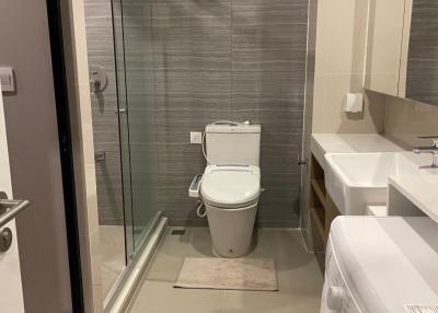 Modern bathroom with glass shower door, toilet, and washing machine