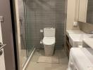 Modern bathroom with glass shower door, toilet, and washing machine