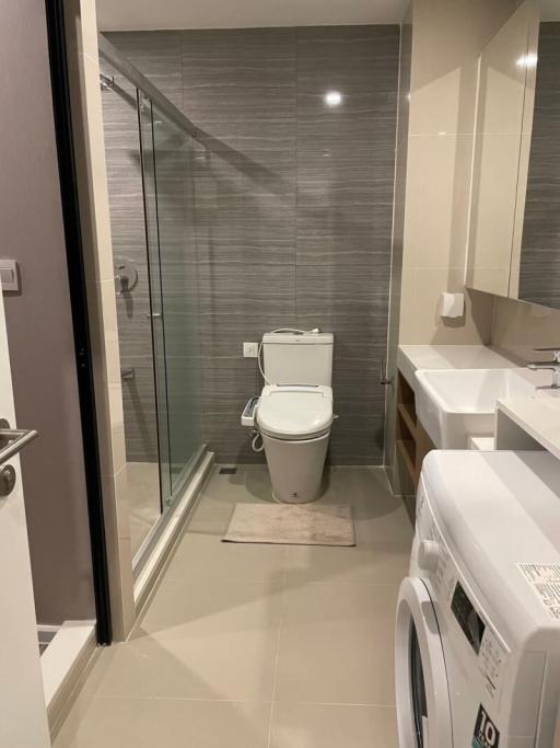 Modern bathroom with glass shower door, toilet, and washing machine
