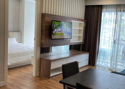 Modern living room with open view to the bedroom, featuring a television and a dining area