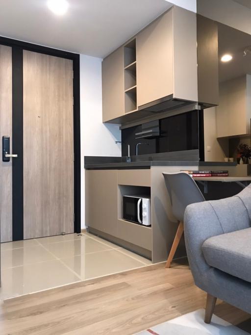 Modern compact kitchen space with sleek appliances and light wood cabinetry adjacent to a cozy living area