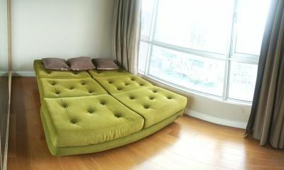 Bright bedroom with large window and green modular sofa bed