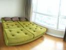 Bright bedroom with large window and green modular sofa bed