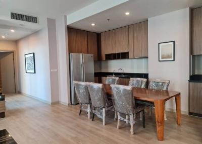 Modern open-plan dining area with adjacent kitchen, featuring wooden finishes and stainless steel appliances