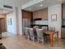 Modern open-plan dining area with adjacent kitchen, featuring wooden finishes and stainless steel appliances