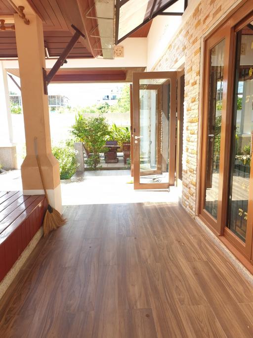 Spacious patio with wood flooring, large glass doors, and outdoor seating area