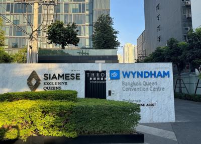 Exterior view of Siamese Exclusive Queens building with modern design and signage